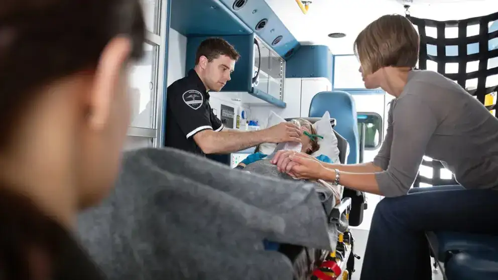Senior woman being given oxygen in an ambulance caregiver at side