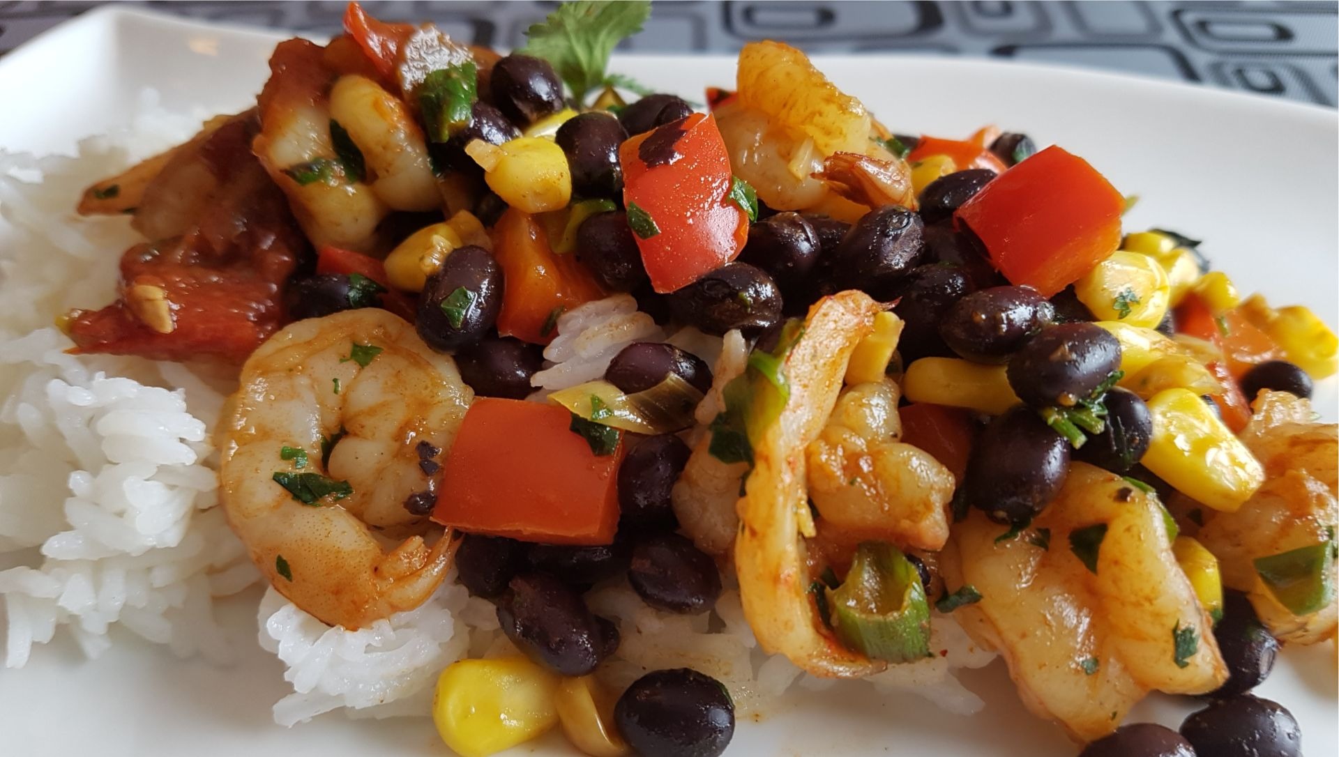 Shrimp, red peppers, black beans, corn, white rice on plate