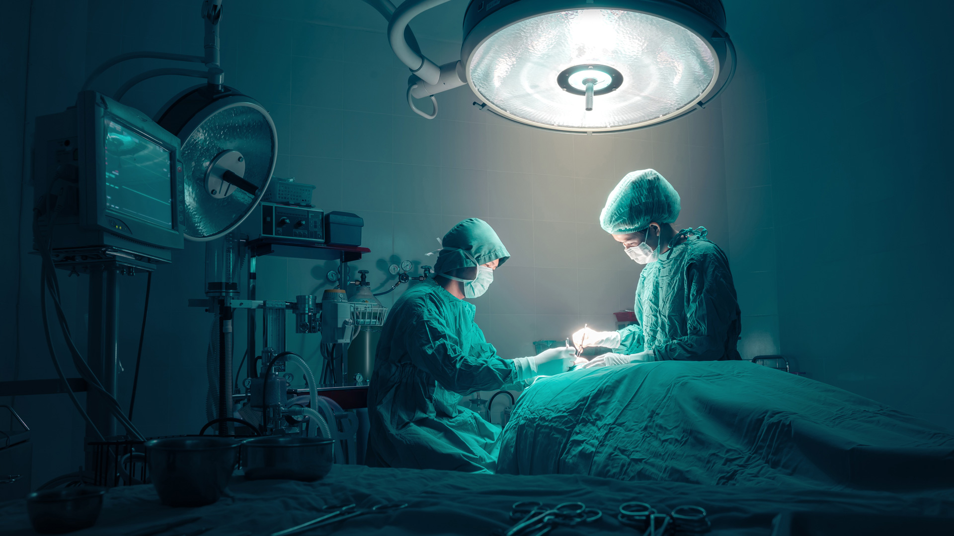 Surgeons team working with monitoring of patient in surgical operating room
