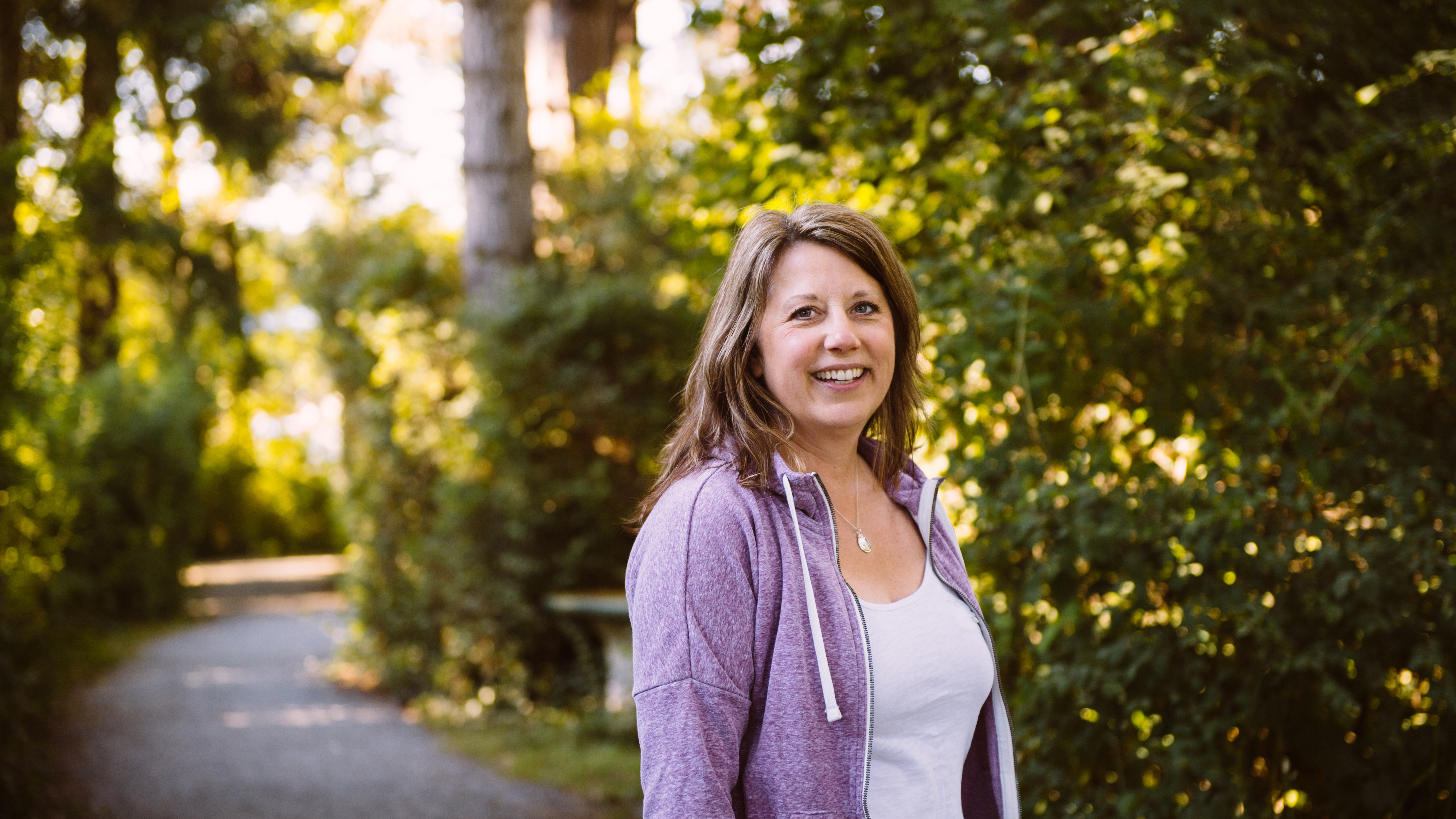 Tracy Bawtinheimer wears a purple jacket surrounded by trees