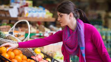 Woman buying oranges in supermarket