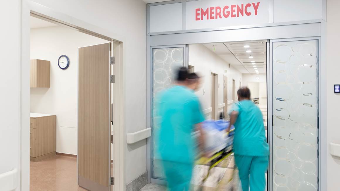 Doctors push a patient on a stretcher in a hospital corridor.