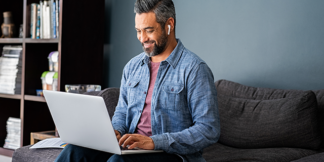 A man sitting on a couch working on his laptop