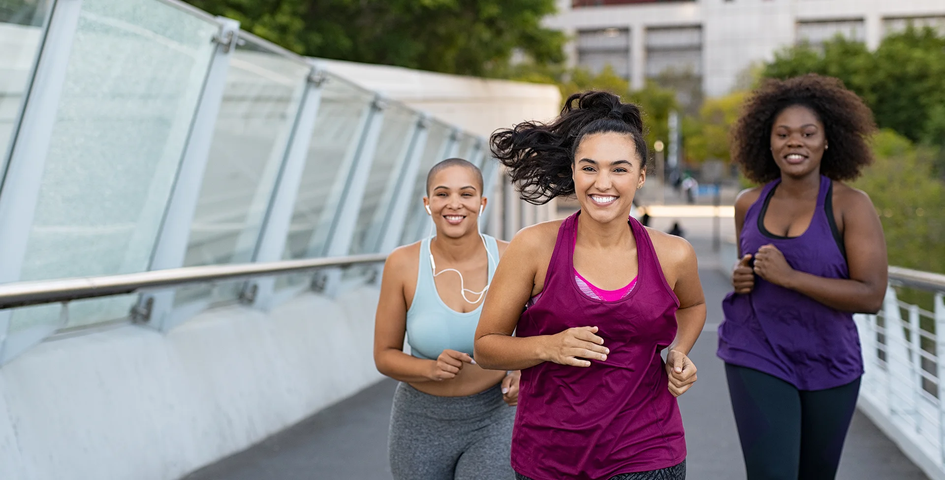 Three women jogging outside in summer weather.