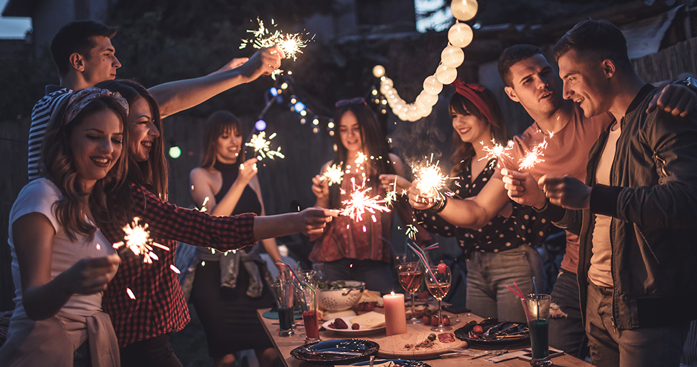 A group of people celebrating with sparklers at night.