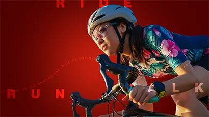 A closeup of a woman racing on her bike with a red background that reads "Ride Run Walk"