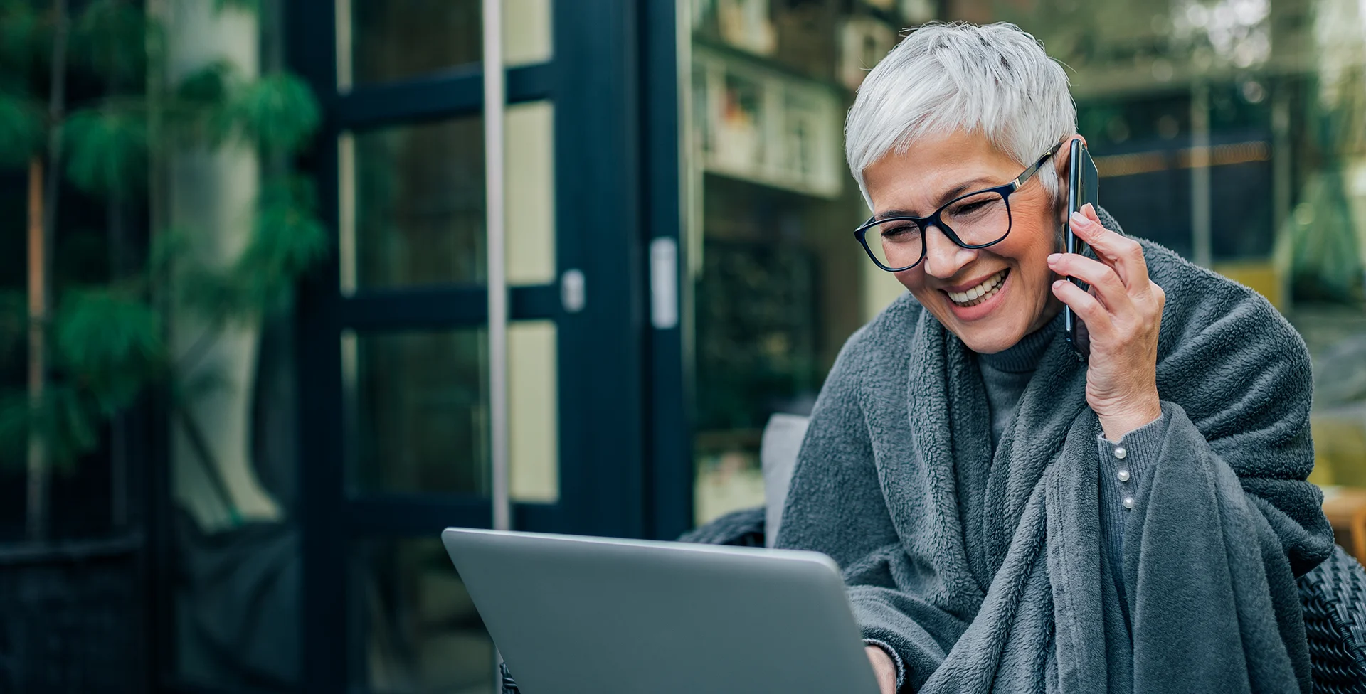 A smiling woman talks on the phone while working on her laptop