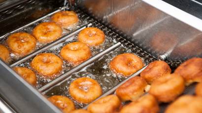 A dozen donuts frying in hot oil