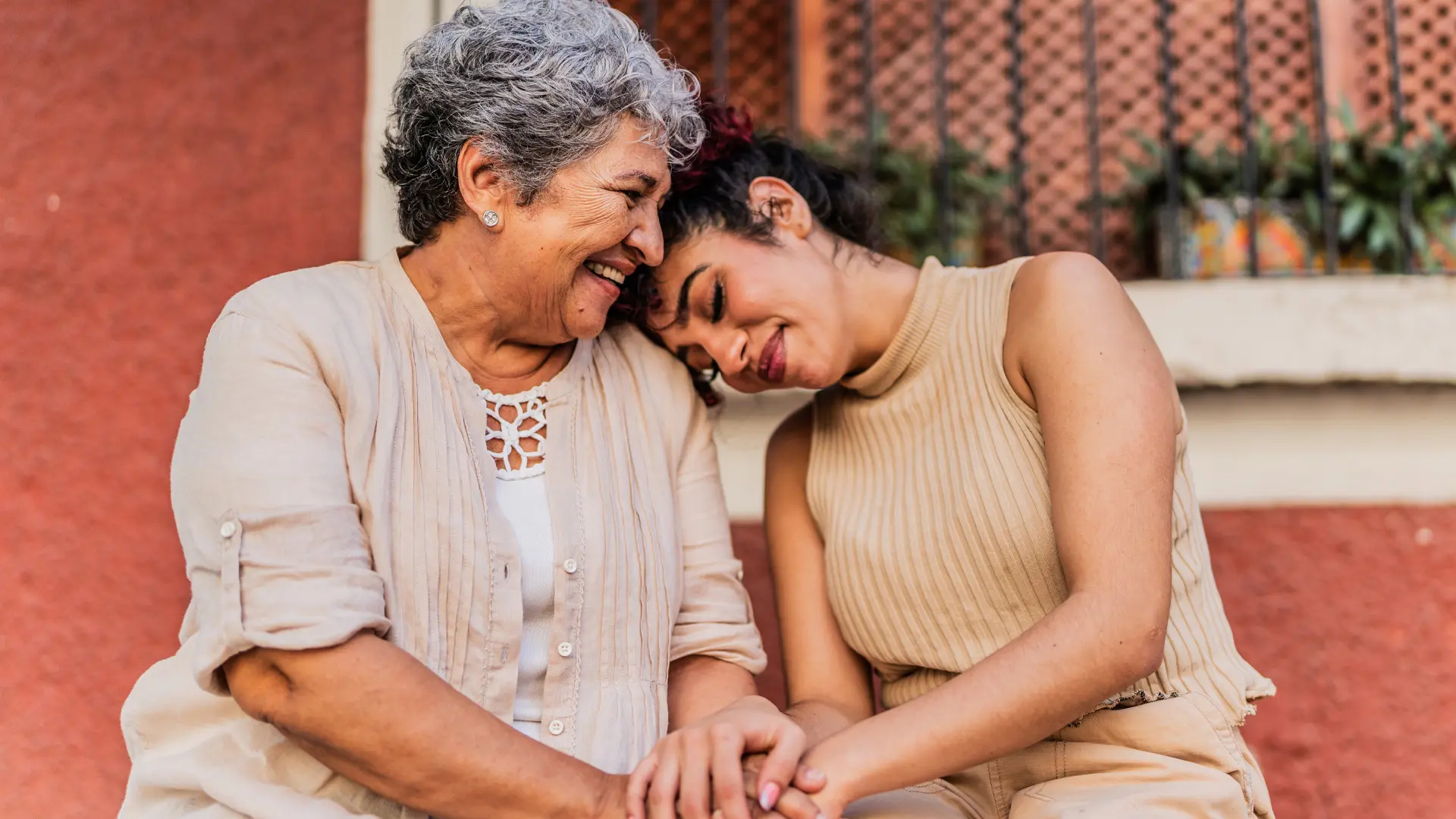 Two women holding hands with one resting her head on the other’s shoulder.