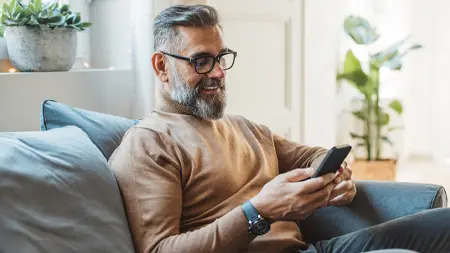 A man using his phone while seated on a couch.