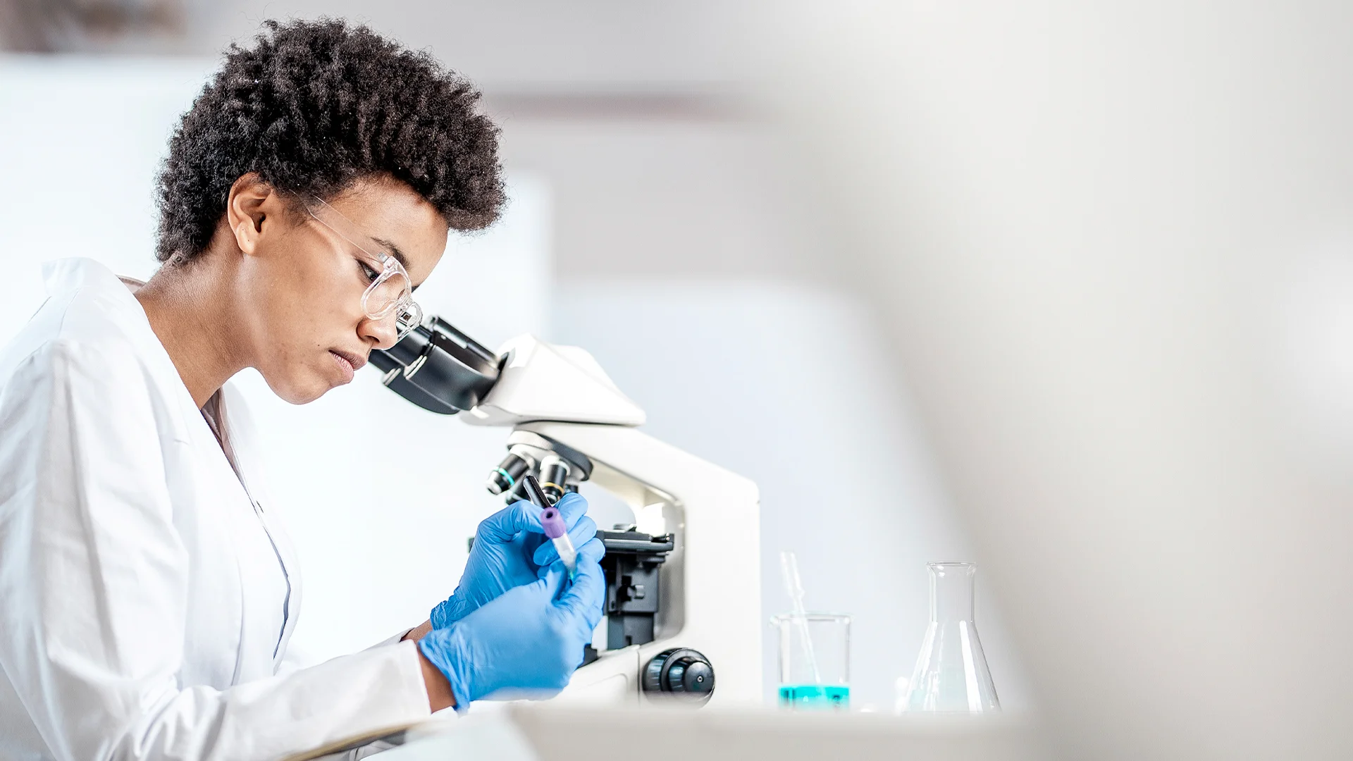 A young researcher using a microscope at a lab.
