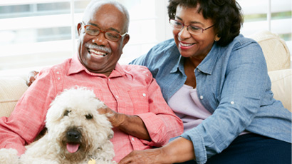 An older couple smiles at their dog.