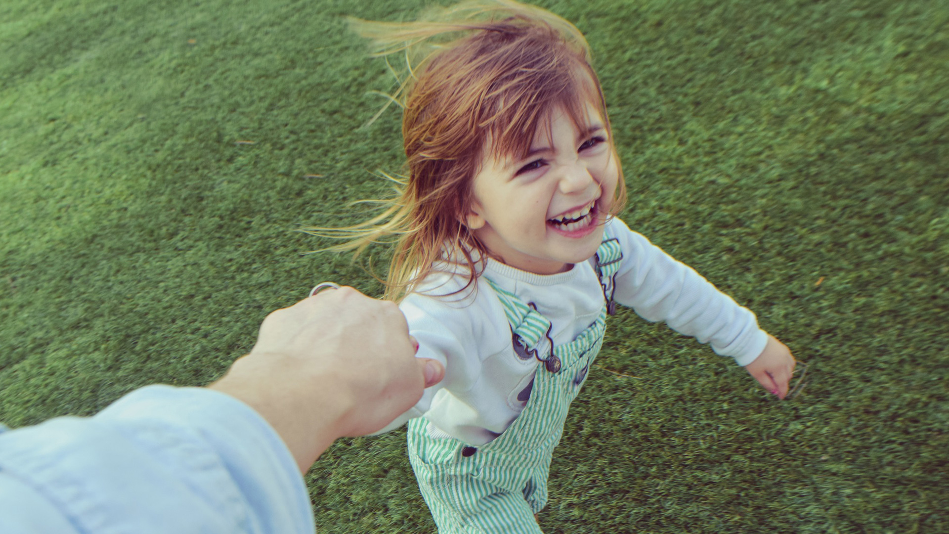 Young girl holding womans hand running outside