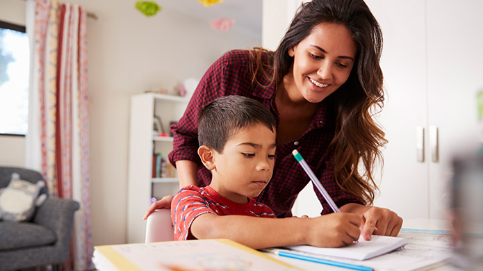 A child and mother working on homework together at the kitchen table.