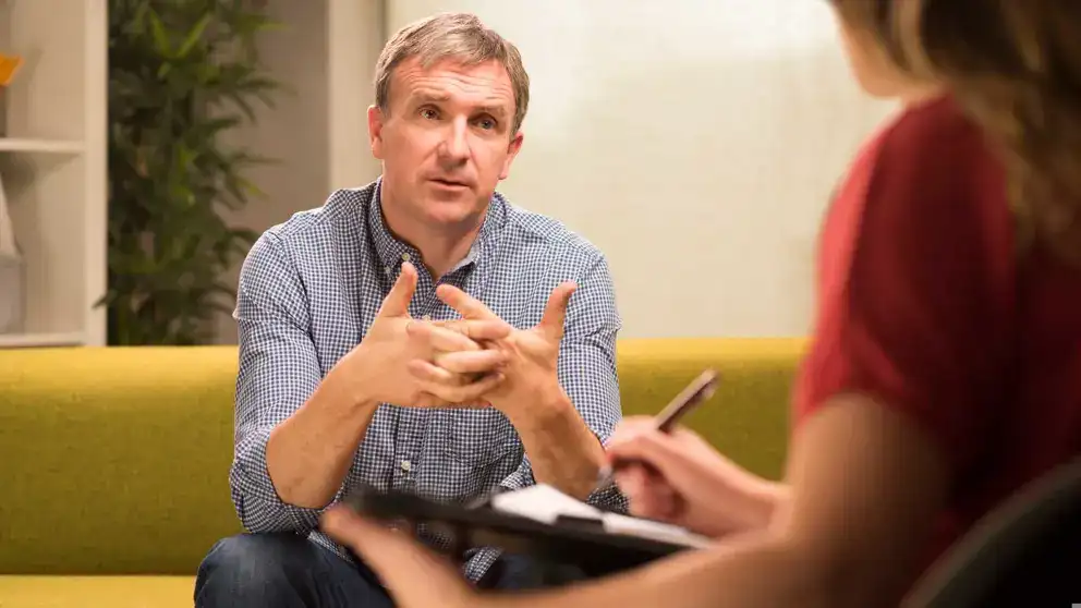 Man sitting on couch speaking to therapist