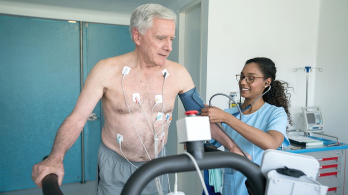 Nurse taking blood pressure of man on treadmill
