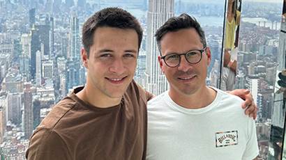 Olivier and his father pose in front of the New York City skyline