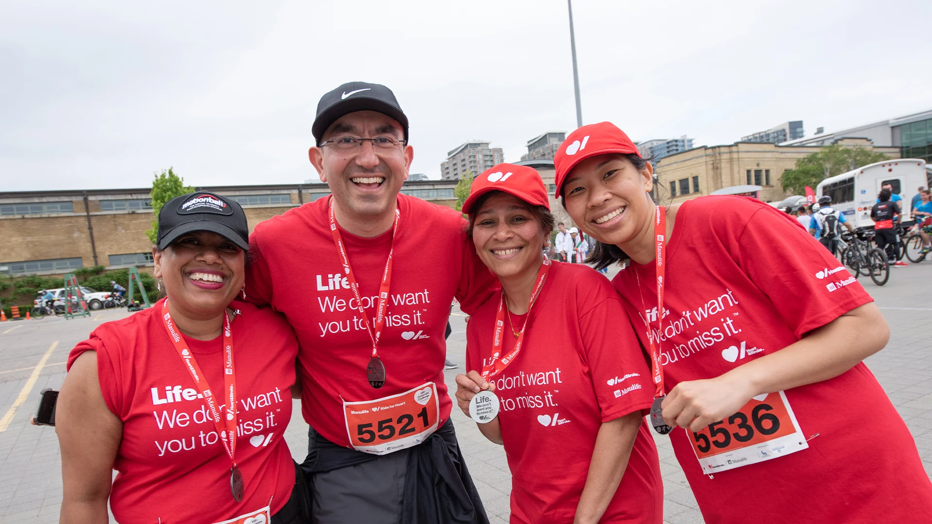 A group of Ride for Heart participants pose for a photo wearing medals and red t-shirts with Heart & Stroke logos.