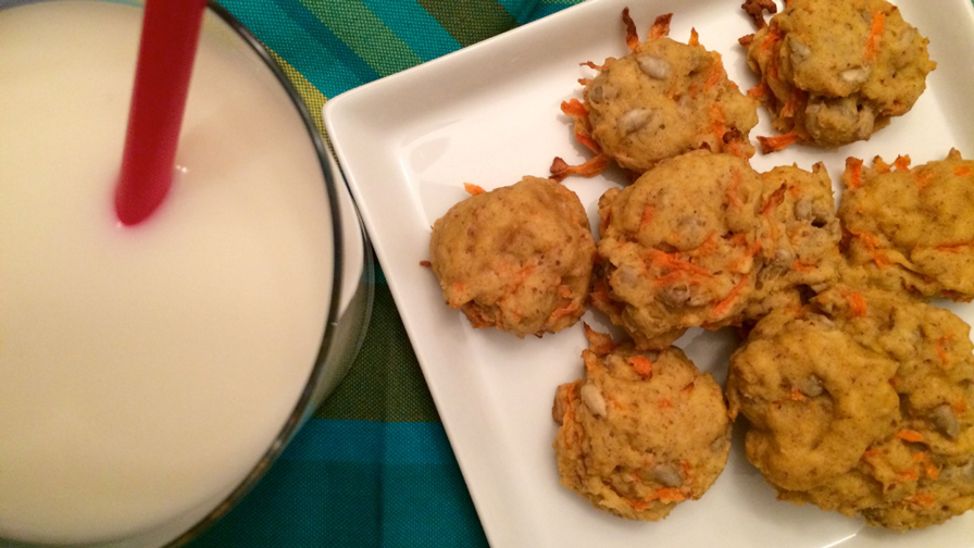 Carrot cookies on a square white plate with a glass of milk with a red straw on the side