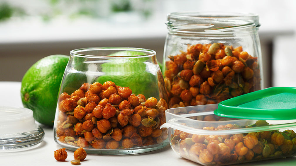  Two glass jars filled with crispy chickpeas, lime in background.