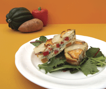 Fun frittata on a bed of greens on a white plate with an orange background