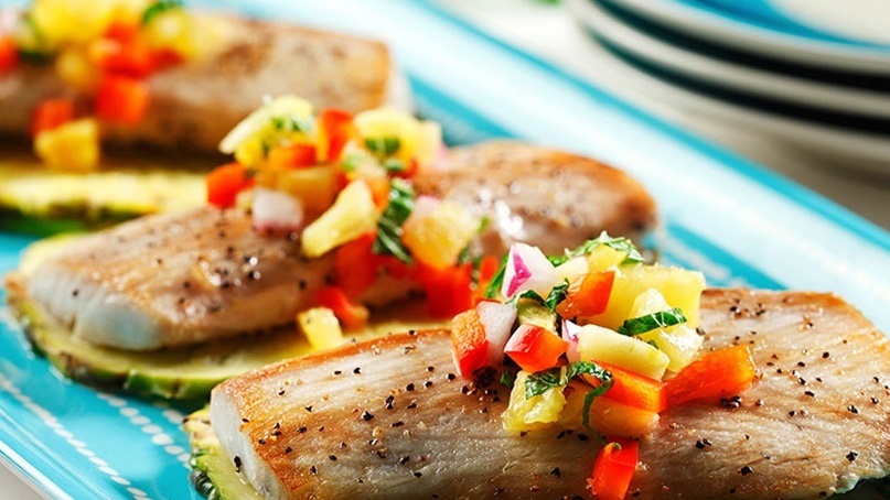 Three pieces of grilled mahi mahi with pineapple salsa on a blue plate