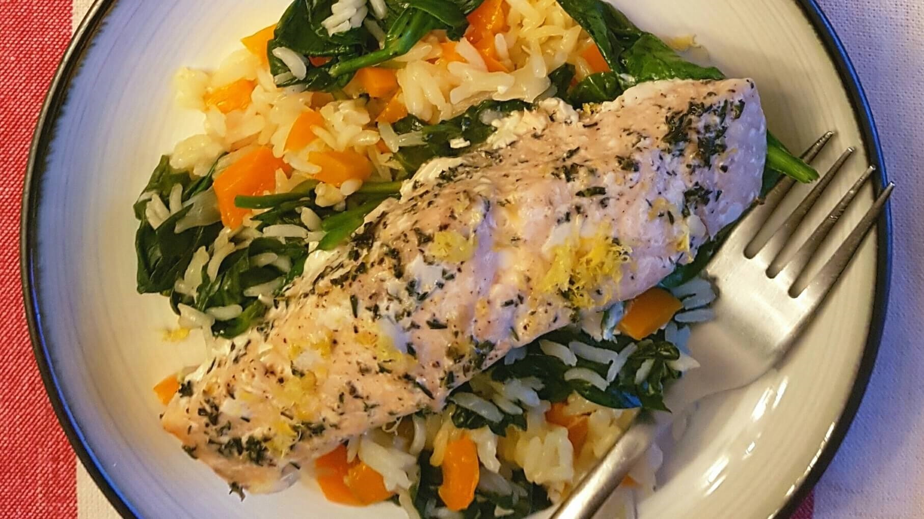 Plate of cooked salmon, spinach, carrots and rice
