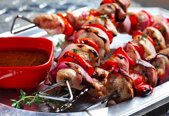 Skewers of grilled chicken and red peppers on plate with marinade
