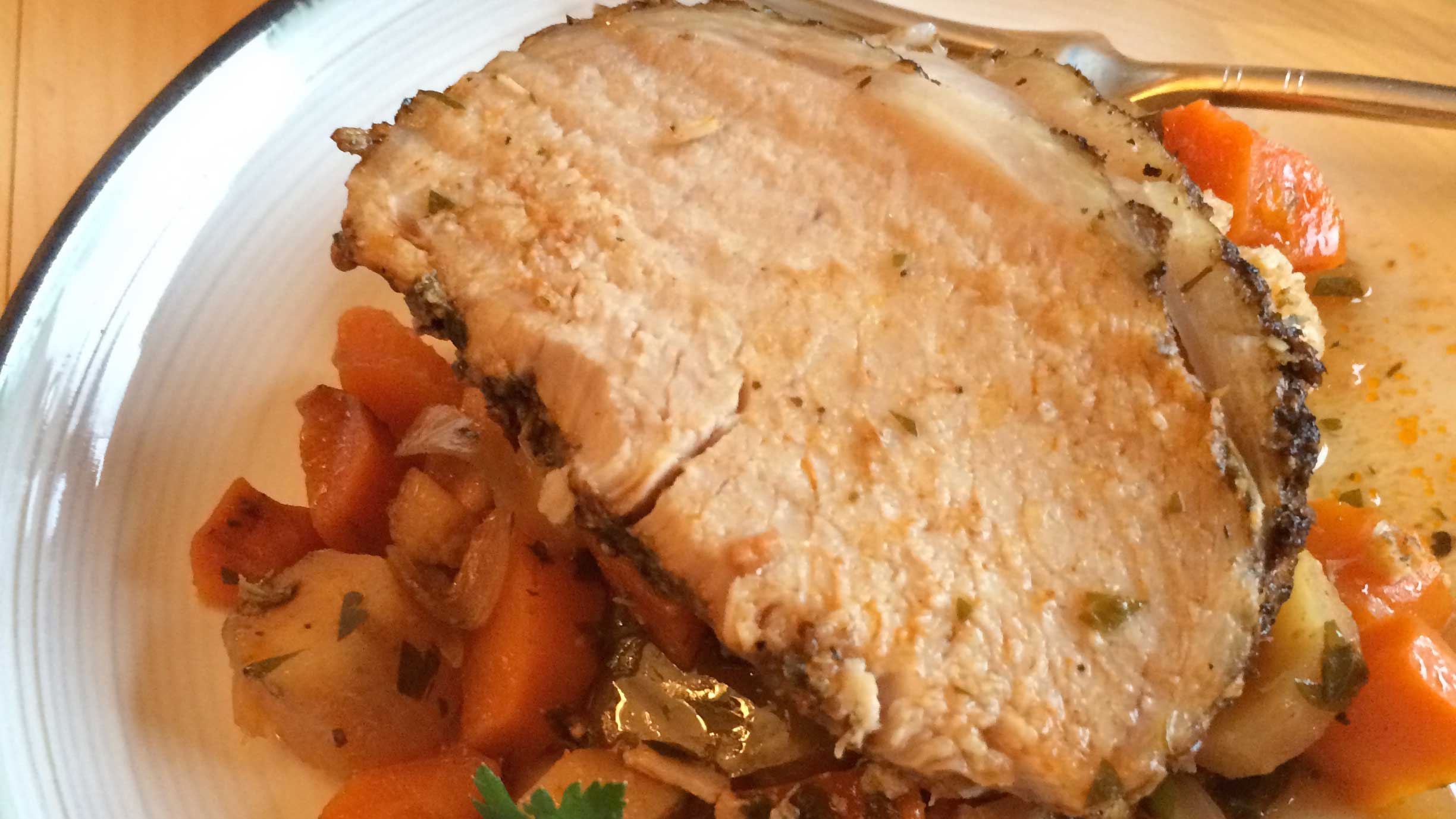 Slow cooker pork roast and veggies on a white plate with a fork