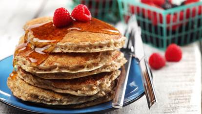 Stack of pancakes on a blue plate topped with raspberries