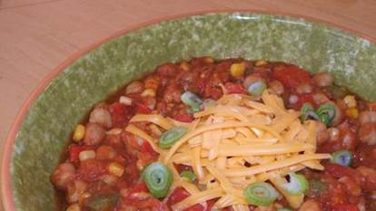 Vegetarian chili in a green bowl with grated cheese.