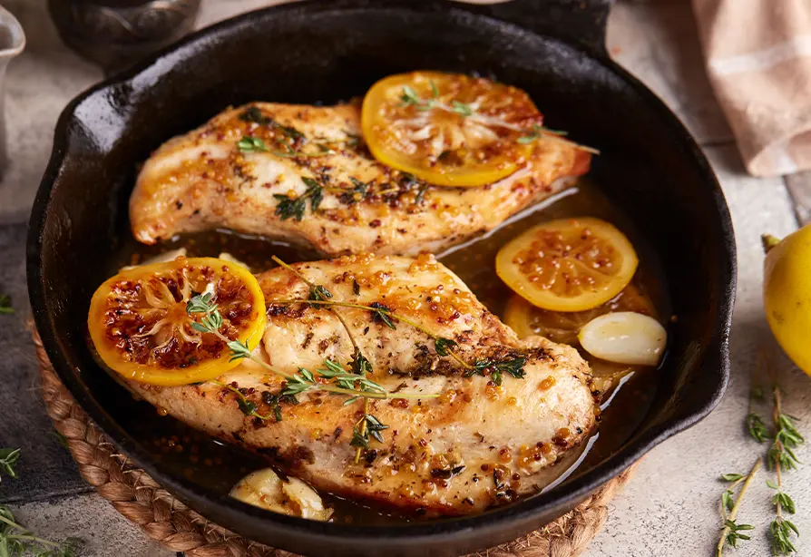 Sliced turkey breast in an iron skillet, topped with fresh herbs
