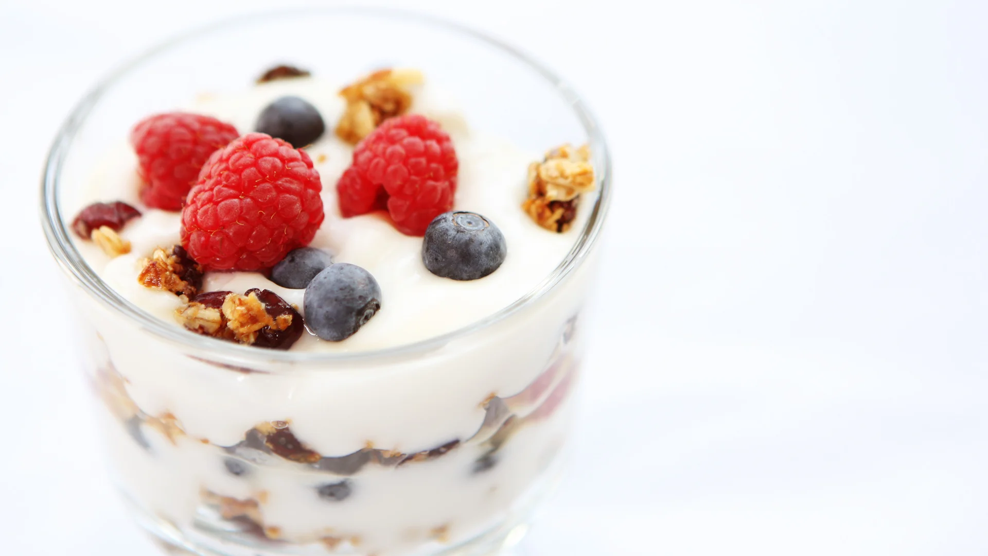 Yogurt and berries with granola in clear glass