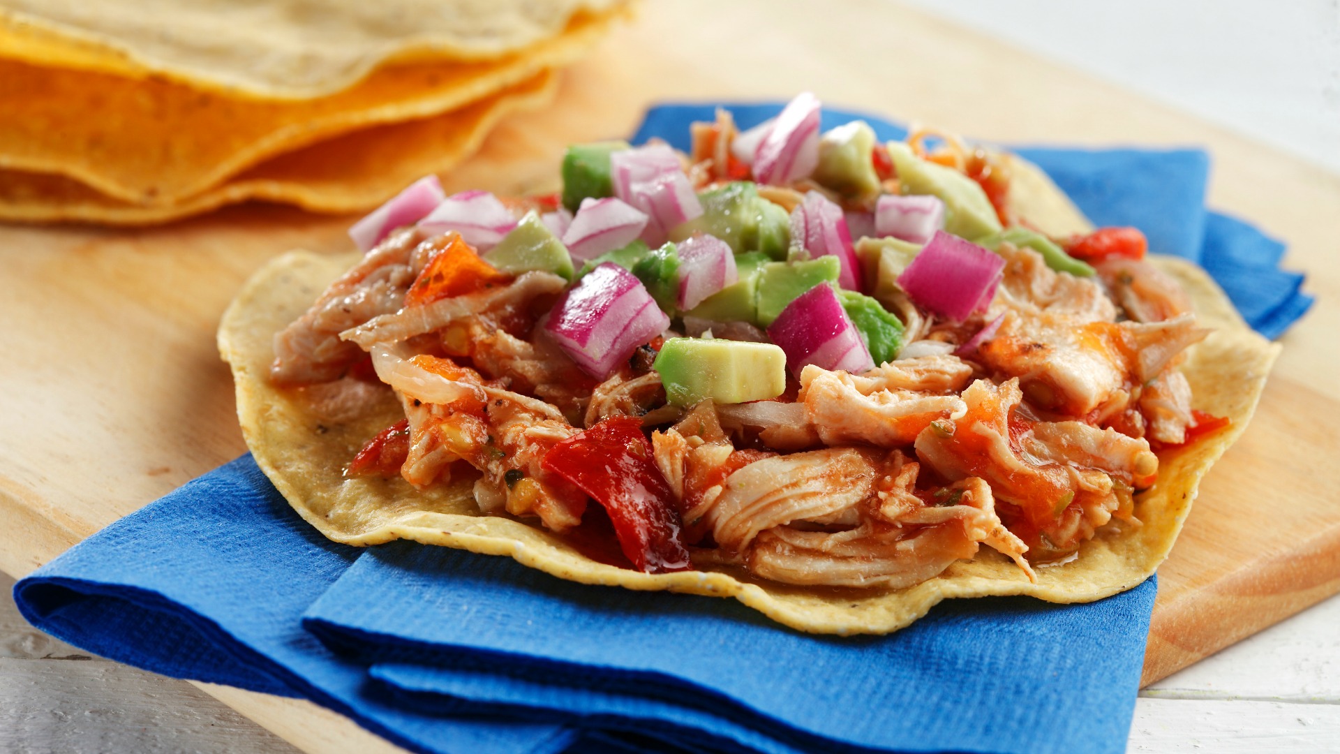 Shredded chicken tostadas with spicy tomato salsa on serving napkins