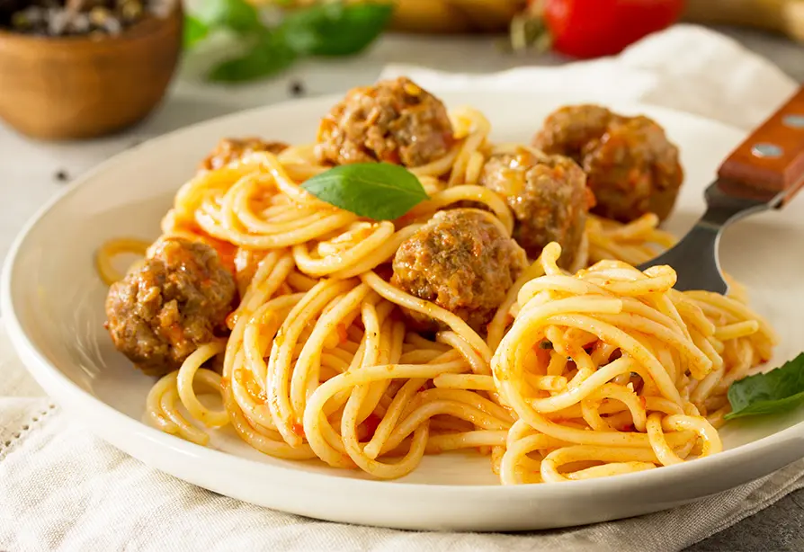 A dish with spaghetti and turkey meatballs with a fork