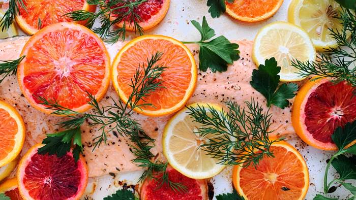 A fillet of salmon covered with citrus slices and herbs