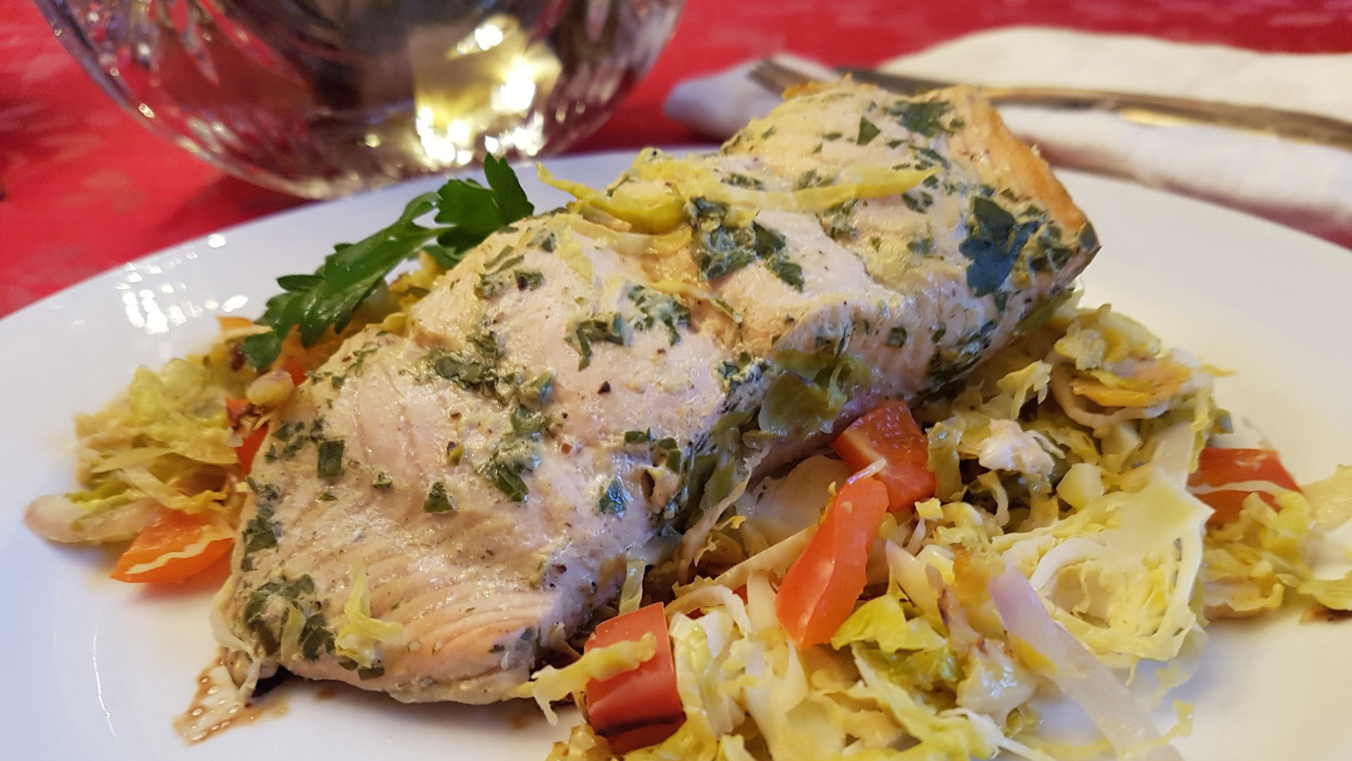 A portion of cooked salmon on top of a bed of Brussels sprouts on a white plate.