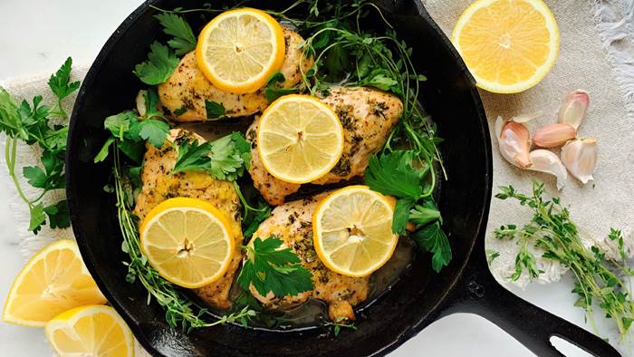 Chicken breasts and lemon slices in a black skillet