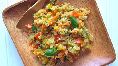 Vegetable confetti quinoa on a wooden plate and a wooden spoon