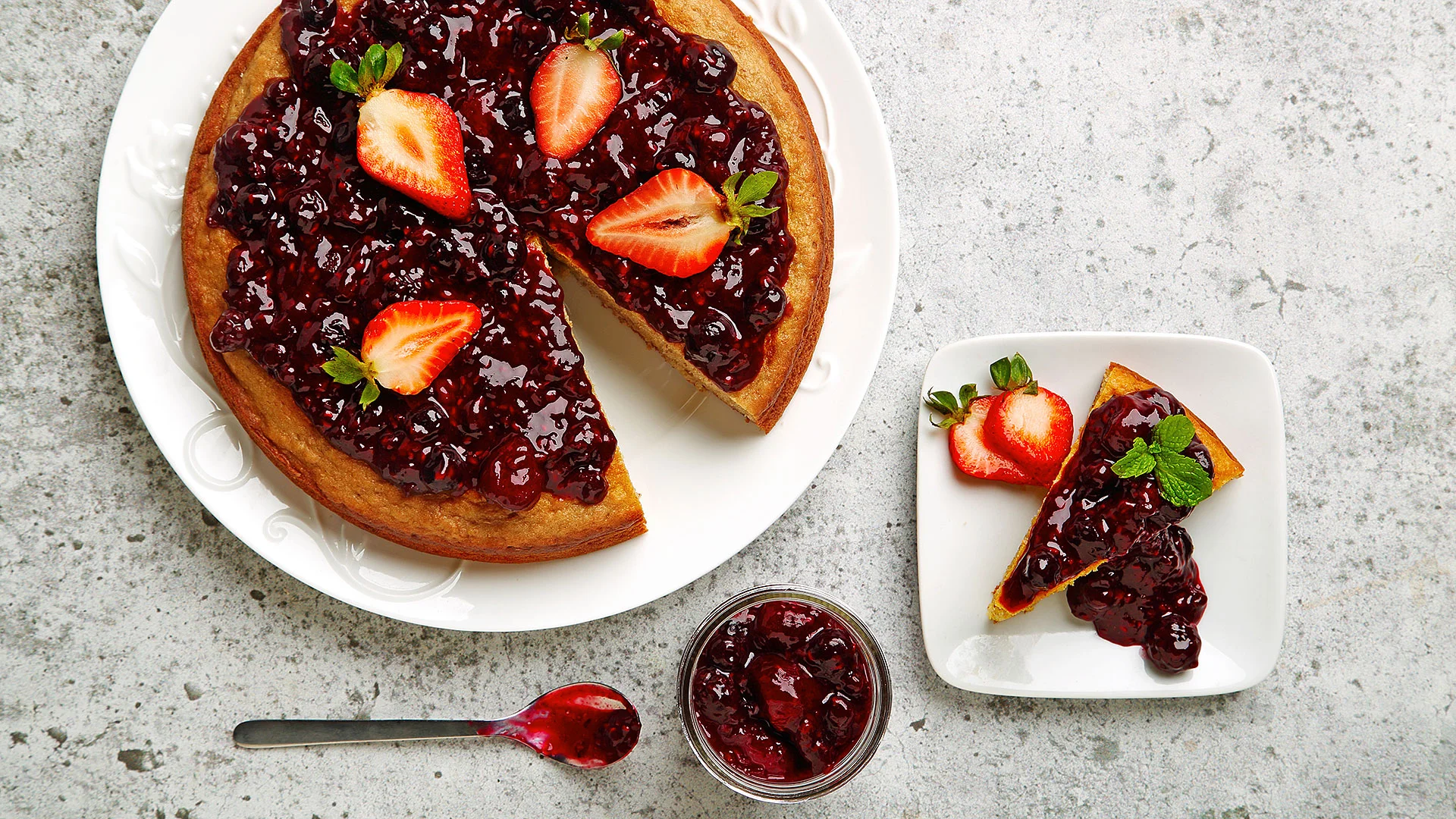 Yogurt lemon cake with berry sauce served on a white plate.