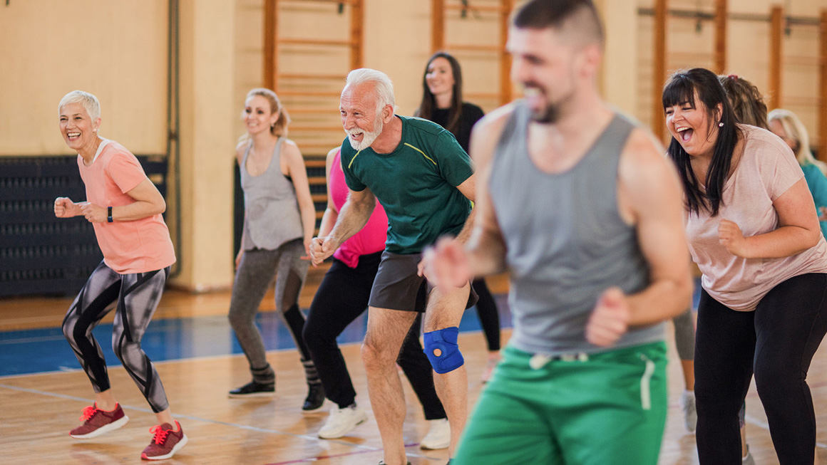 Smiling and happy group of people dancing at gym