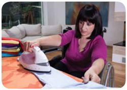 A young woman ironing the sleeve of a white shirt.