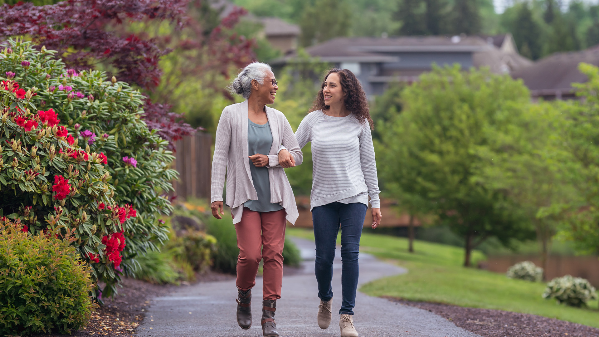 A senior woman and her adult daughter walking through a garden