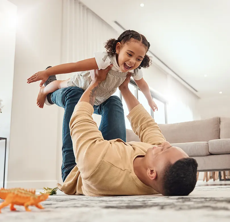 A father playing with his daughter at home.