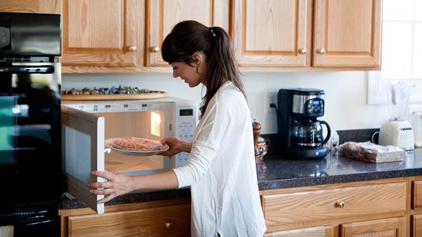 Woman in kitchen using a microwave