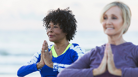 Two women doing beach yoga