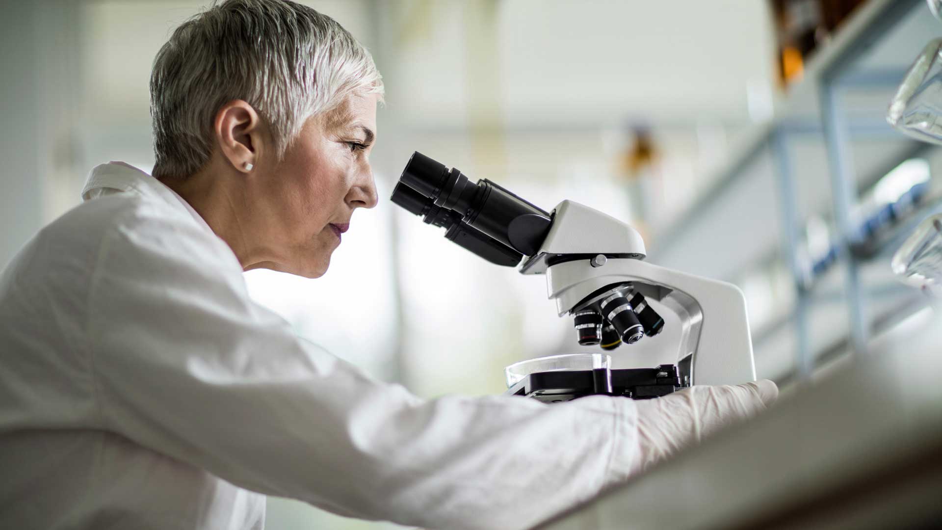 Female researcher using microscope in lab