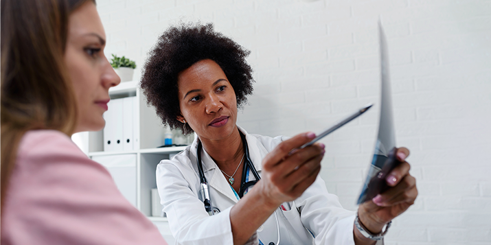 A doctor explains information on a paper to a woman patient.