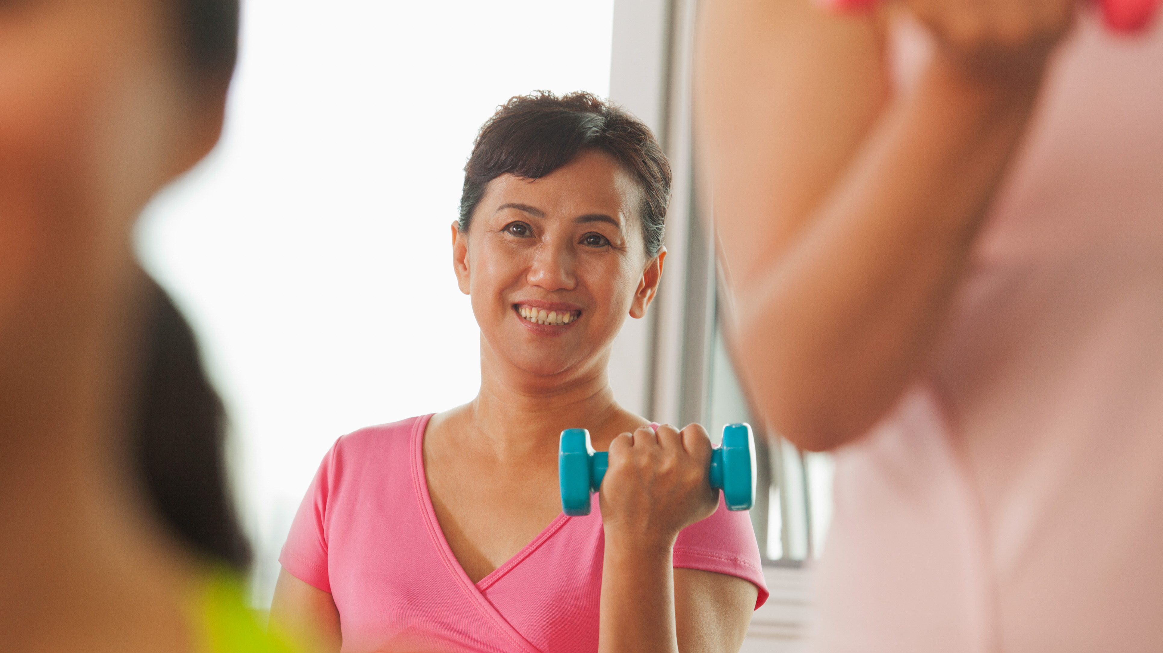 mature woman lifting weights in gym