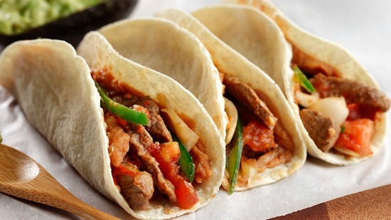 Three tortillas filled with steak, red and green peppers and salsa